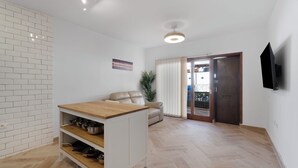 Ein modernes Wohnzimmer mit Kücheninsel, einer Couch und einem an der Wand befestigten Fernseher.