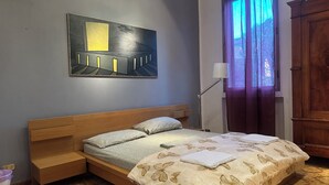 A bedroom with a bed, a nightstand, a lamp, a window with curtains, a wooden cabinet, and a painting on the wall. - Bnb Fantasia (Bologna)
