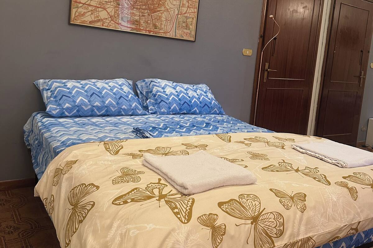 A bedroom with a bed, a wall map, a wardrobe, and an air conditioning unit.