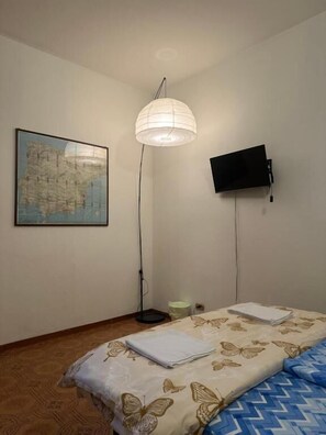 A bedroom with a bed, a map on the wall, a TV, and a floor lamp. - Bnb Fantasia (Bologna)
