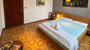 A hotel room with a bed, a small table with a tray, a painting on the wall, and a ceiling light fixture. - Bnb Fantasia (Bologna)