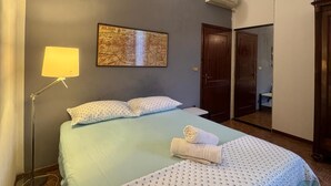 A hotel room with a bed, a map on the wall, a lamp, and a door leading to a bathroom. - Bnb Fantasia (Bologna)