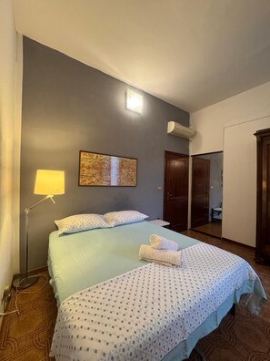 A hotel room with a bed, a map on the wall, a lamp, and a door leading to a bathroom. - Bnb Fantasia (Bologna)