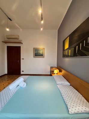A hotel room with a bed, a painting, a lamp, and a ceiling light. - Bnb Fantasia (Bologna)