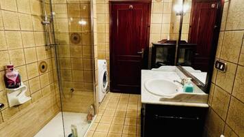 Un bagno con box doccia in vetro, lavandino, specchio e WC.
