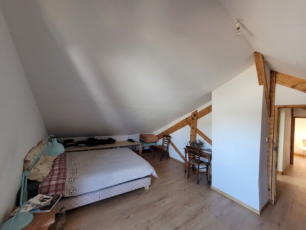 A bedroom with a loft bed, a desk, and a chair.