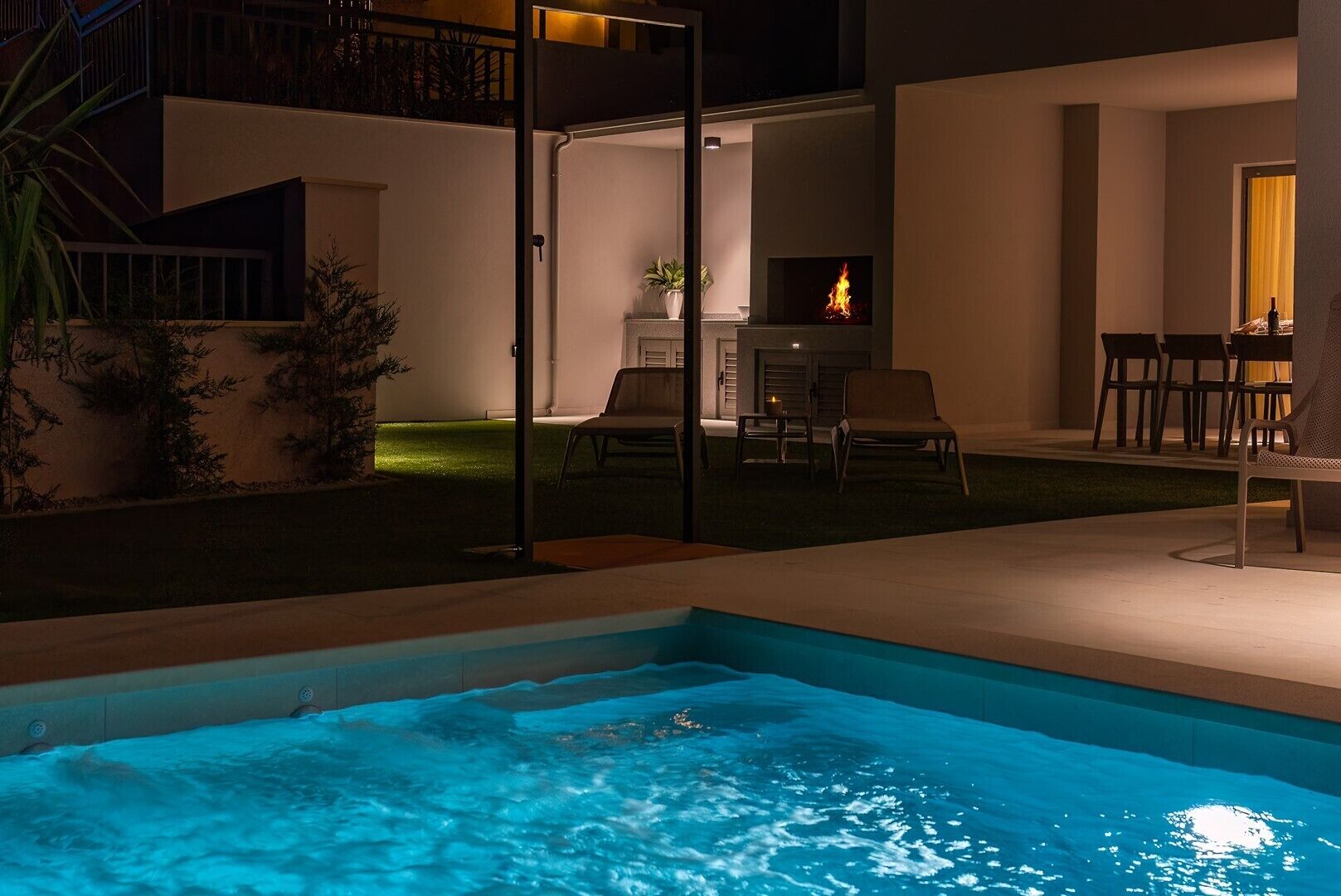 Ein Pool mit Feuerstelle, Sitzgelegenheiten im Freien und einer Terrassenfläche.