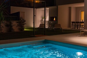 Ein Pool mit Feuerstelle, Sitzgelegenheiten im Freien und einer Terrassenfläche.
