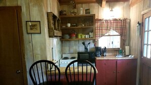 A kitchen with wooden cabinets, a stove, a microwave, and two black chairs.