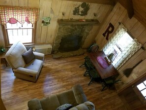 Una habitación acogedora con chimenea de piedra, paredes de madera, una mesa de comedor con sillas y un sofá.