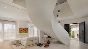Un salon moderne doté d’un plafond incurvé, d’un canapé, d’une table basse et d’une bibliothèque.