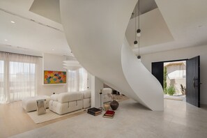 Ein modernes Wohnzimmer mit gewölbter Decke, einem Sofa, einem Couchtisch und einem Bücherregal.