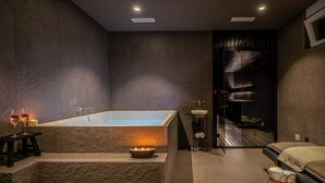 Une salle de bain moderne avec une grande baignoire, un petit lavabo et un porte-serviettes.