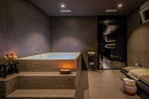 Ein modernes Badezimmer mit einer großen Badewanne, einem kleinen Waschbecken und einem Handtuchhalter.