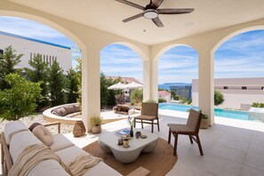 Ein sonniger Außenbereich mit Pool, Sitzgelegenheiten und Deckenventilator.