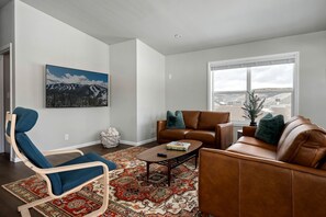 Ein Wohnzimmer mit einer Couch, einem Sessel, einem Couchtisch und einem großen Fenster mit Blick.