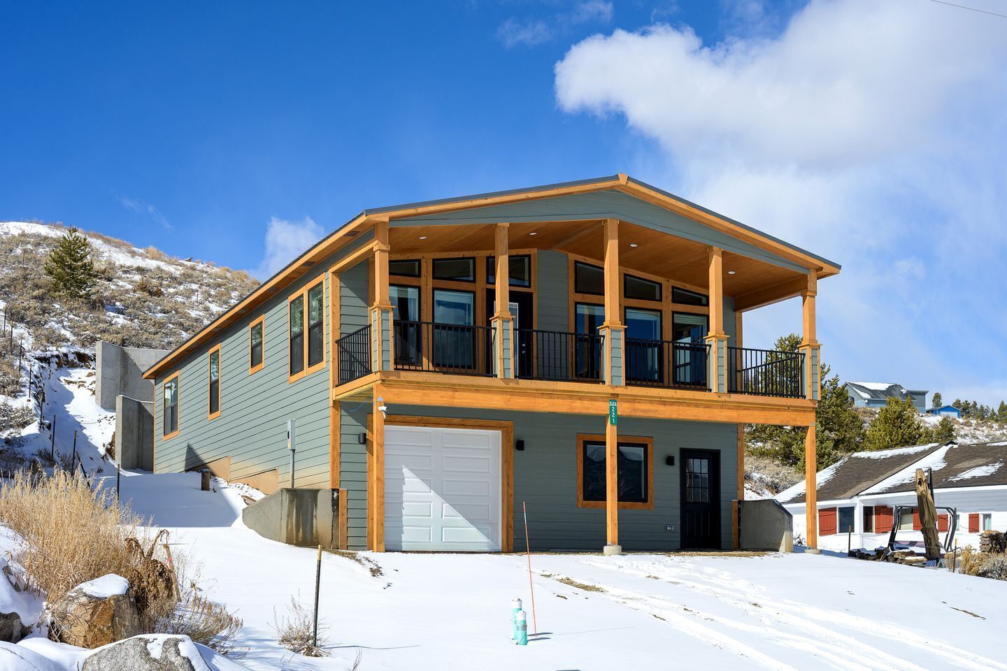 A two-story house with a balcony, a garage, and a snow-covered landscape.