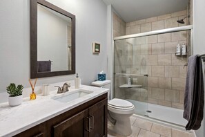 Ein Badezimmer mit zwei Waschbecken, einer Toilette, einer Dusche mit Glastüren und einem Spiegel.