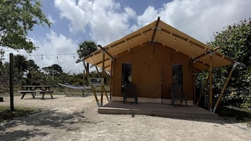 Eine Zelthütte mit Picknicktisch und Stühlen, umgeben von Bäumen.