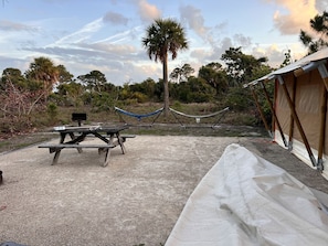 A camping area with a picnic table, hammock, and a tent.