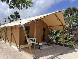 A tent with a wooden deck, a welcome sign, and a chair. - Comfortable Double Safari Tent Near Jonathan Dickinson State Park in Hobe Sound, FL (Hobe Sound)