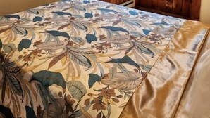 Une chambre à coucher avec une couvre-lit à motifs floraux, des murs en bois et une fenêtre avec des rideaux.