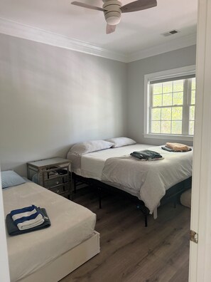 Une chambre à coucher avec un lit, une table de chevet, une fenêtre et un ventilateur de plafond.