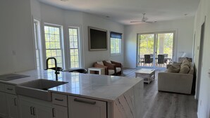 A spacious kitchen with a large island, a dining area with a sofa and chairs, and a sliding glass door leading to an outdoor patio. - 3-bedroom marsh views in Litchfield by the Sea with many amenities (Pawleys Island)
