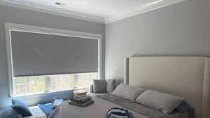 A bedroom with a large window, a bed with a headboard, and a bedside table with pillows and folded blankets. - 3-bedroom marsh views in Litchfield by the Sea with many amenities (Pawleys Island)