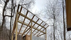 A wooden cabin with a staircase leading to a covered porch.