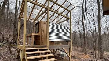 A wooden cabin with a staircase leading to a covered porch.