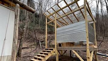 A wooden structure with a metal roof, a staircase, and a small enclosed area.