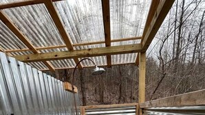 A small, enclosed space with a wooden frame, metal walls, and a gravel floor.