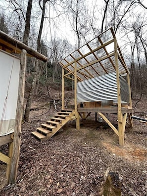 Una estructura de madera con techo de metal, una escalera y un espacio pequeño cerrado.