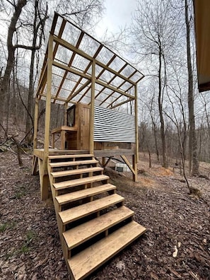 A wooden cabin with a staircase leading to a covered porch.