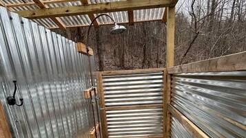 A small, enclosed space with a wooden frame, metal walls, and a gravel floor.