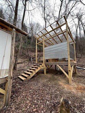 Eine Holzhütte mit einem Metall-Dach, einer Treppe und einem kleinen, abgeschlossenen Bereich.