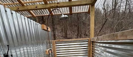 A small, enclosed space with a wooden frame, metal walls, and a gravel floor.