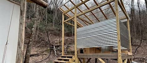 Una estructura de madera con techo de metal, una escalera y un espacio pequeño cerrado.
