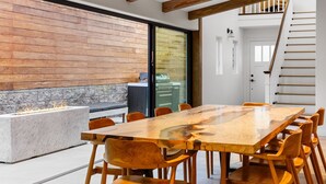 Een moderne eethoek met een grote houten tafel, stoelen en een stenen open haard.