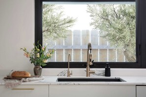 Eine Küche mit Fenster, Blumen in einer Vase, einem Brotlaib und einem Wasserhahn.