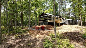 Eine Holzhütte mit einer Holzterrasse und einer überdachten Veranda, umgeben von einem Wald.