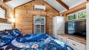 Ein Schlafzimmer mit Bett, Fernseher, Kleiderschrank und Fenster.