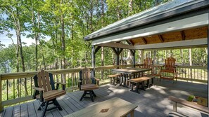 Eine Holzterrasse mit Tischen und Stühlen, umgeben von Bäumen.
