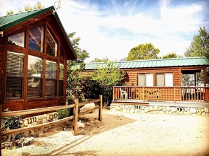 Een houten chalet met grote ramen, een stenen fundering en een groen dak.
