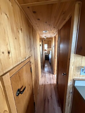 A wooden hallway with a door on the left and a window on the right.