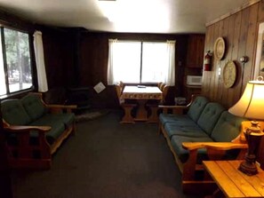 Ein gemütliches Wohnzimmer mit Kamin, Holzmöbeln und Blick ins Freie.