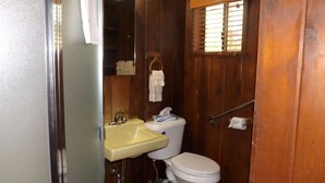 Et lille badeværelse med vask, toilet og vindue.