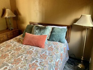 Un letto con biancheria da letto floreale, una testiera in legno e due lampade da comodino.
