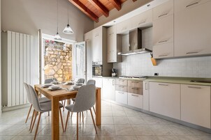 Una cocina moderna con comedor, pared de piedra y vigas de madera en el techo.